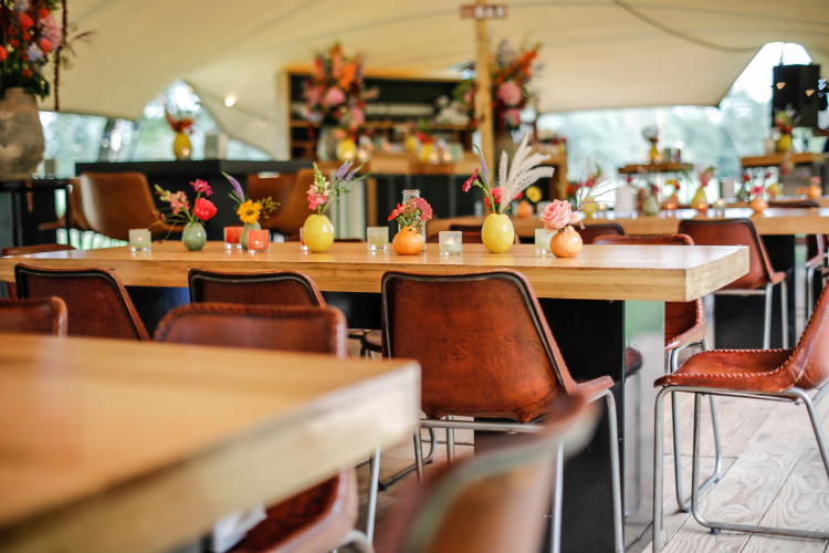 Sfeervolle opstelling met strakke tafels, krukken en stoelen in combinatie met een moderne bar – verzorgd door Westerhuis Verhuur