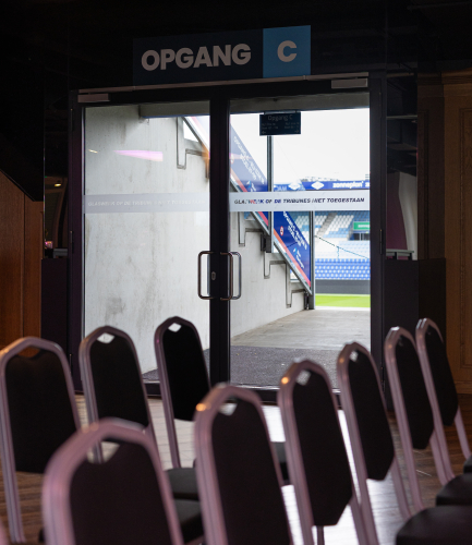 Event ruimte met stoelen en uitzicht op een voetbalveld