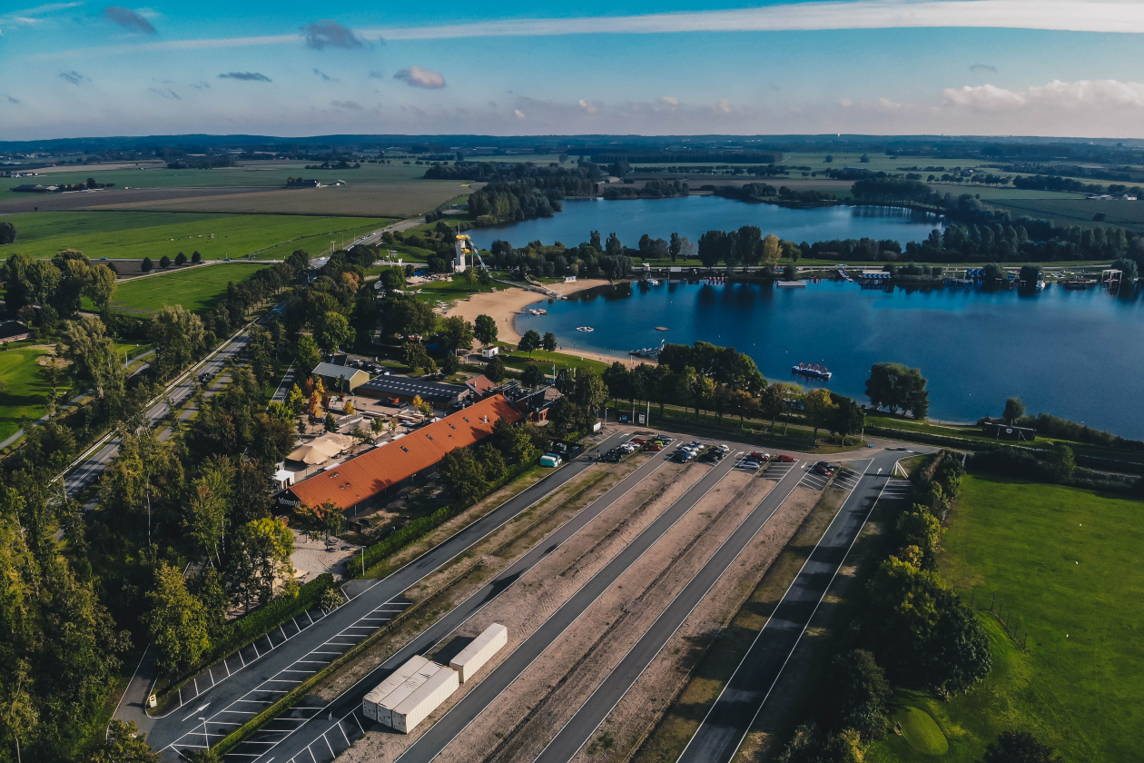 Overzicht van het terrein, met de parking, hoofdgebouw en het water.