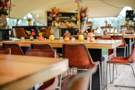 Sfeervolle opstelling met strakke tafels, krukken en stoelen in combinatie met een moderne bar – verzorgd door Westerhuis Verhuur