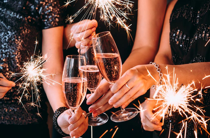 Dames die een glaasje cava en vuurwerk vasthouden