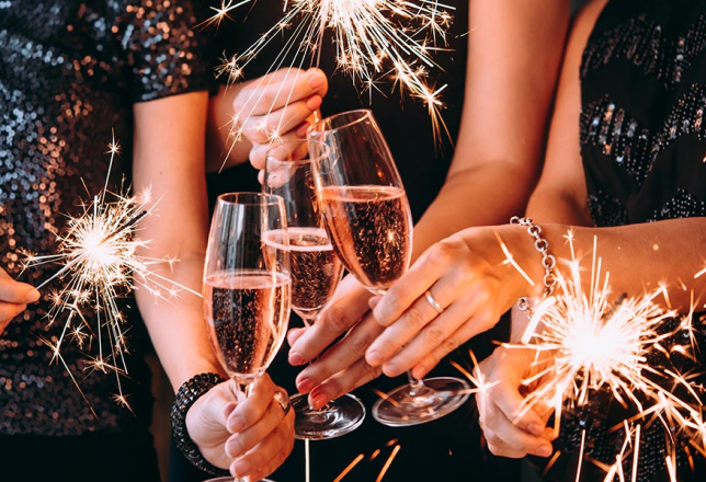 Dames die een glaasje cava en vuurwerk vasthouden